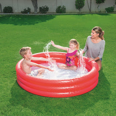 Kinder spielen im roten Bestway Splash-n-Smile-Planschbecken neben einer erwachsenen Person im Garten