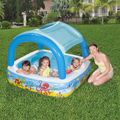 Kinder spielen im Bestway Beach Buddy Planschbecken mit Dach auf dem Rasen neben einer erwachsenen Aufsichtsperson