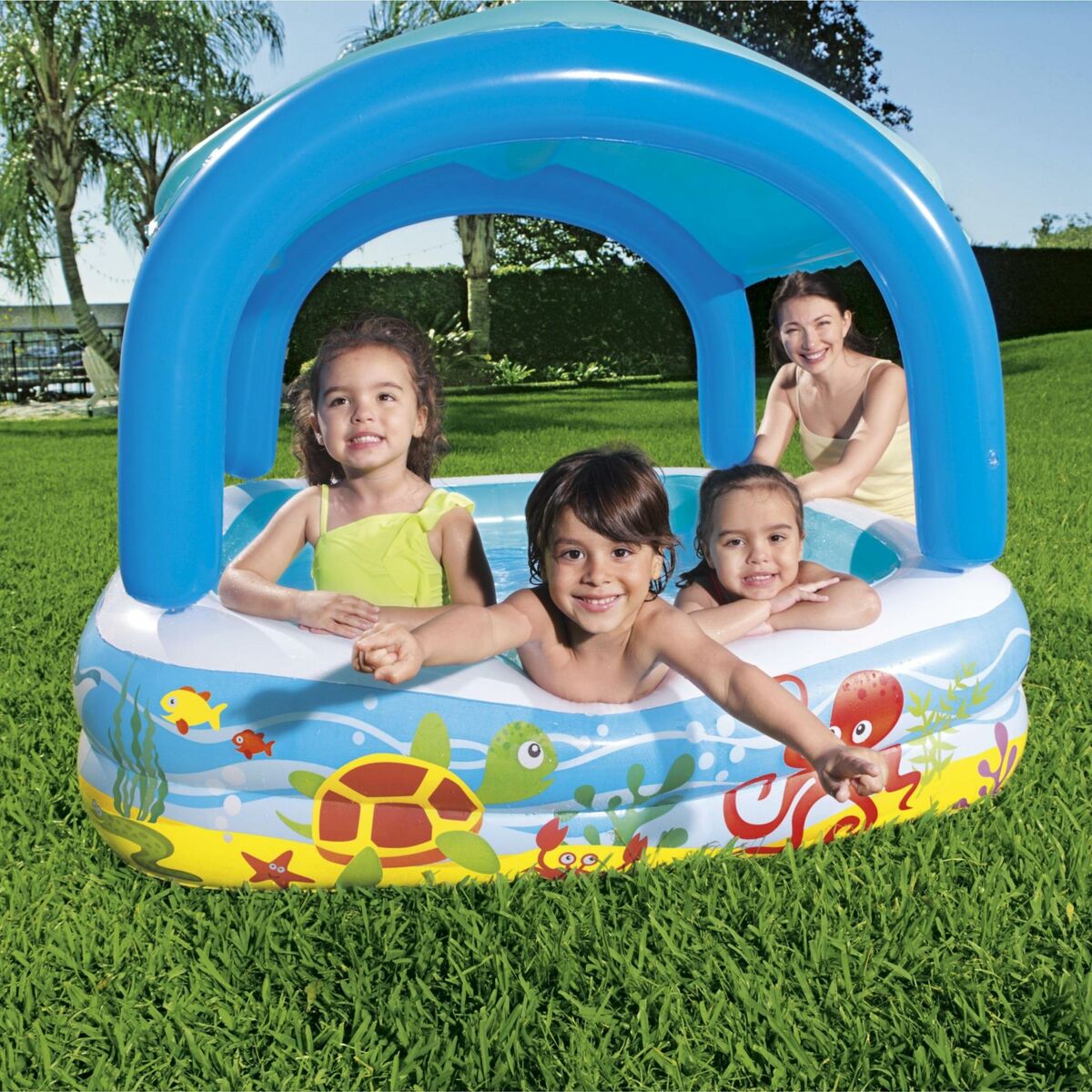 Vorderansicht des Bestway Beach Buddy Planschbeckens mit Meeresmotiven, Kindern und einer erwachsenen Aufsichtsperson im Garten
