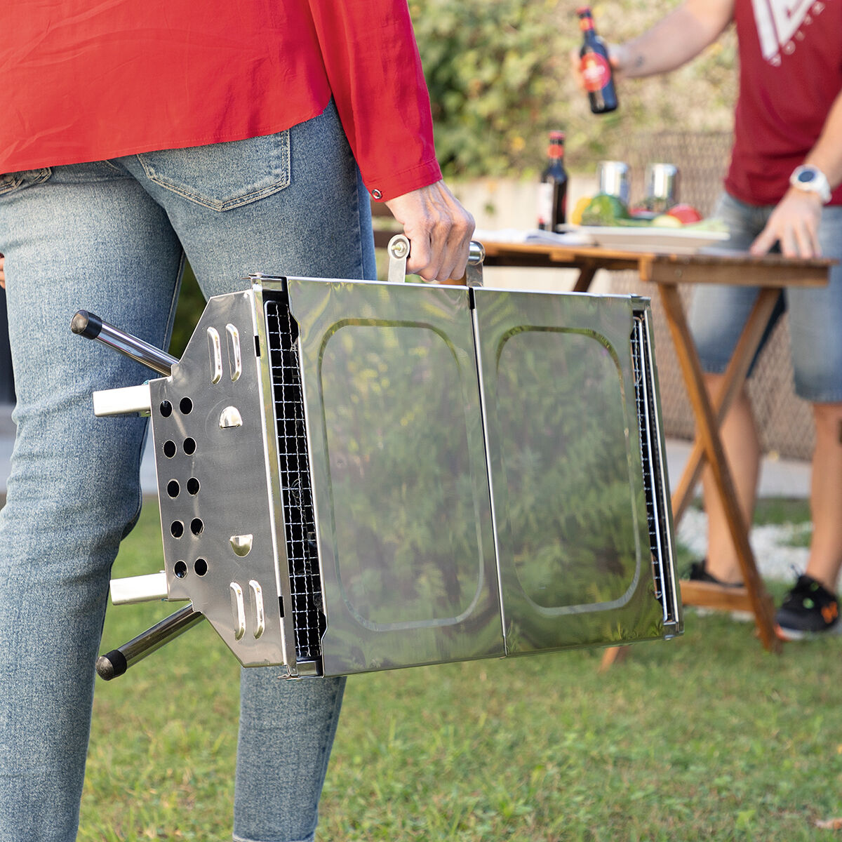 Zusammengeklappter ExelQ-Grill wird am festen Griff getragen