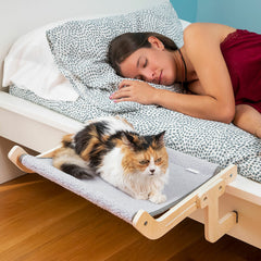 Katzenhängematte Hamacat am Bettrand mit Katze und schlafender Person