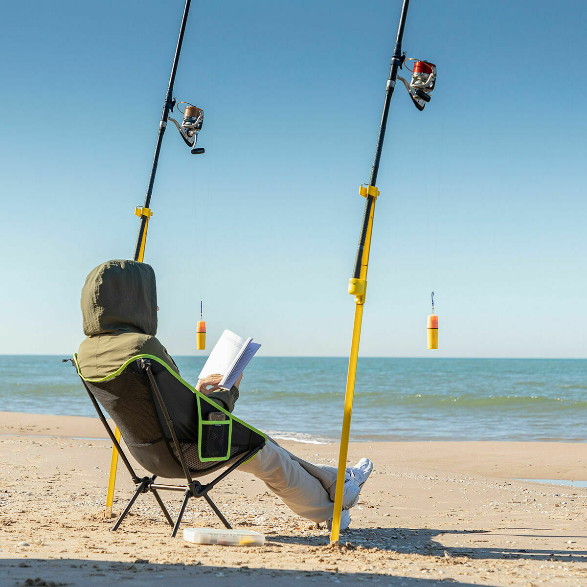 Grün-schwarzer Folstul Campingstuhl am Strand neben weiteren Strandgegenständen