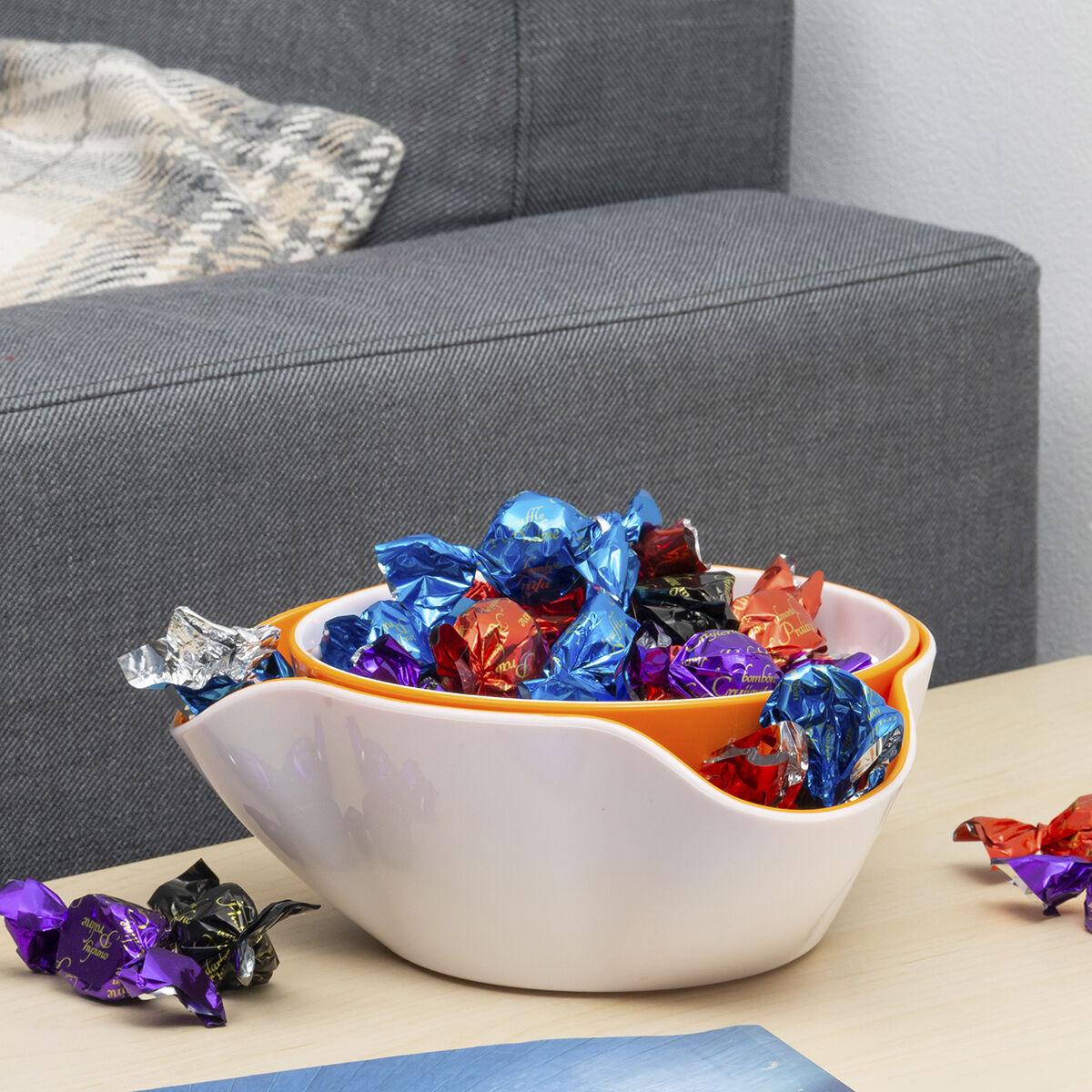 Weiße Snackschale mit gewelltem Rand und Süßigkeiten neben einem Sofa
