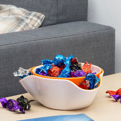Weiße Snackschale mit gewelltem Rand und Süßigkeiten neben einem Sofa