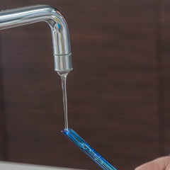 Wasser wird durch den Glasstiel einer Aqua-Loon-Kugel eingefüllt