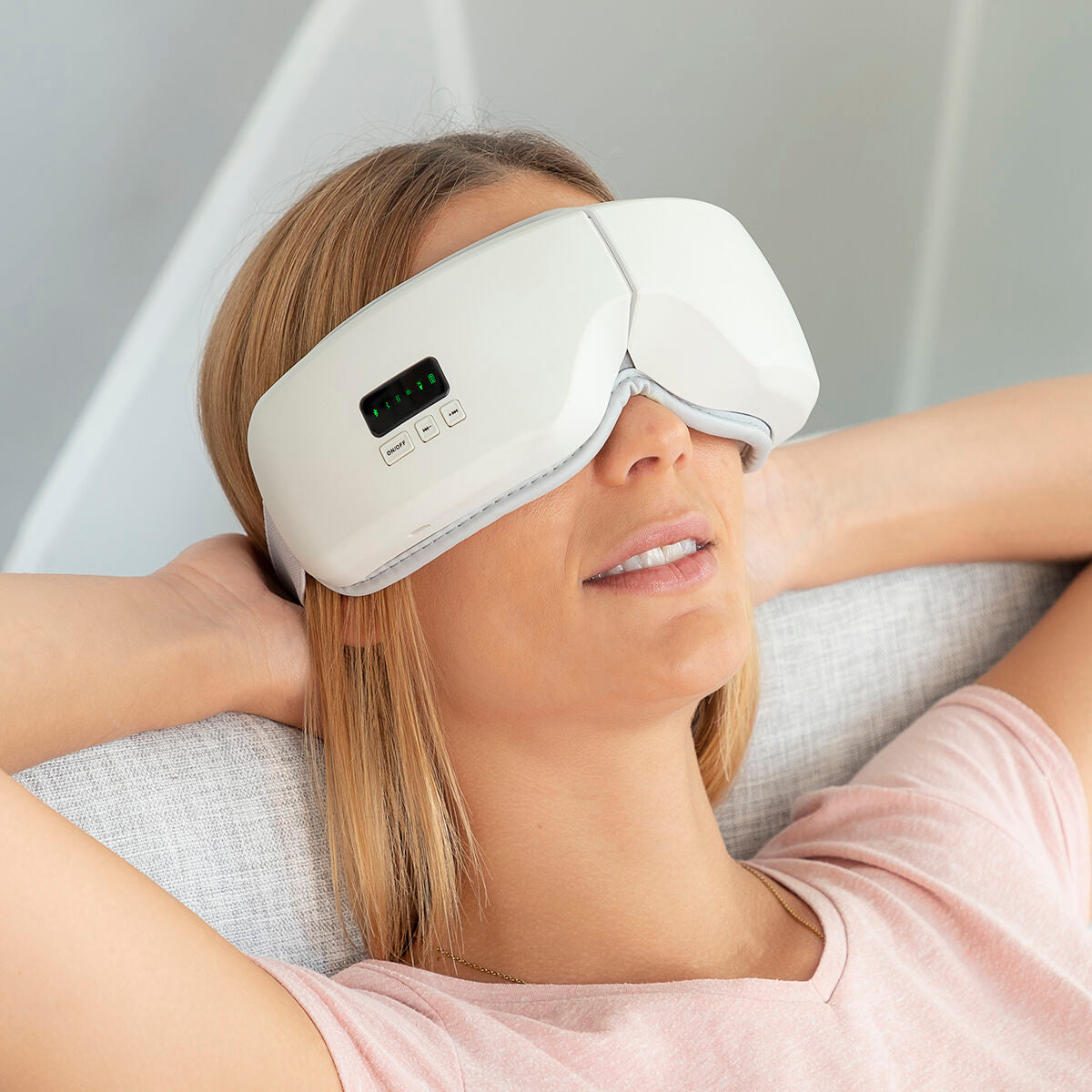 Person trägt die Eyesky-Massagebrille zurückgelehnt auf einem Sitzplatz