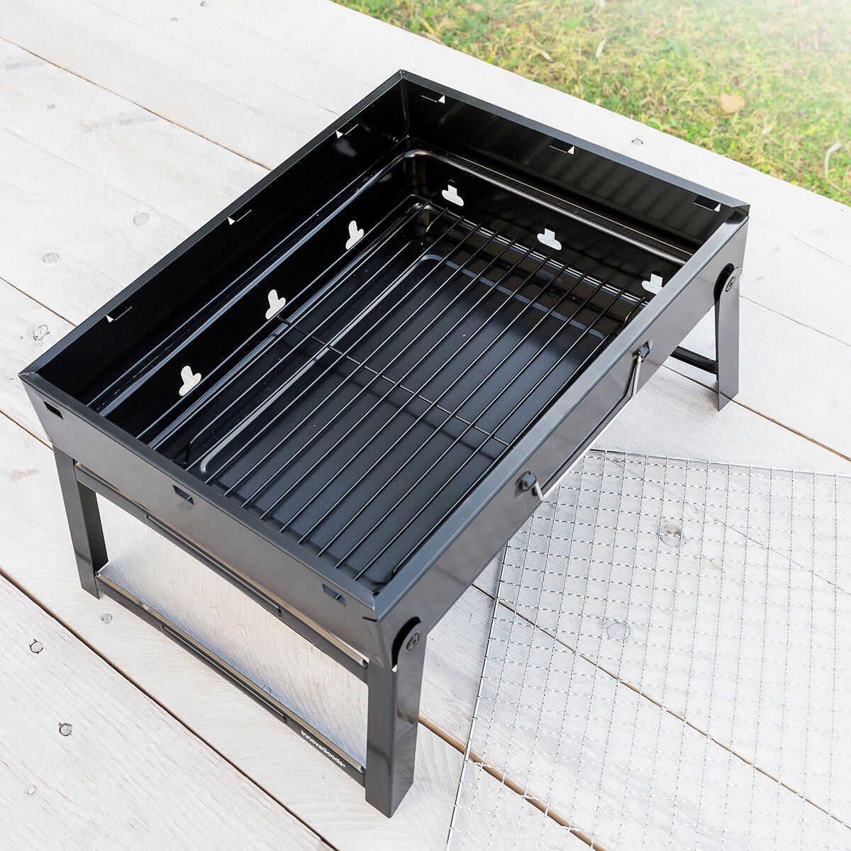 Leerer BearBQ-Grill mit unterem Kohlerost; Grillrost liegt daneben