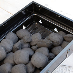 Holzkohle auf dem unteren Kohlerost des BearBQ-Grills