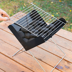 Grillrost wird auf den mit Holzkohle bestückten Foldecue-Grill aufgelegt