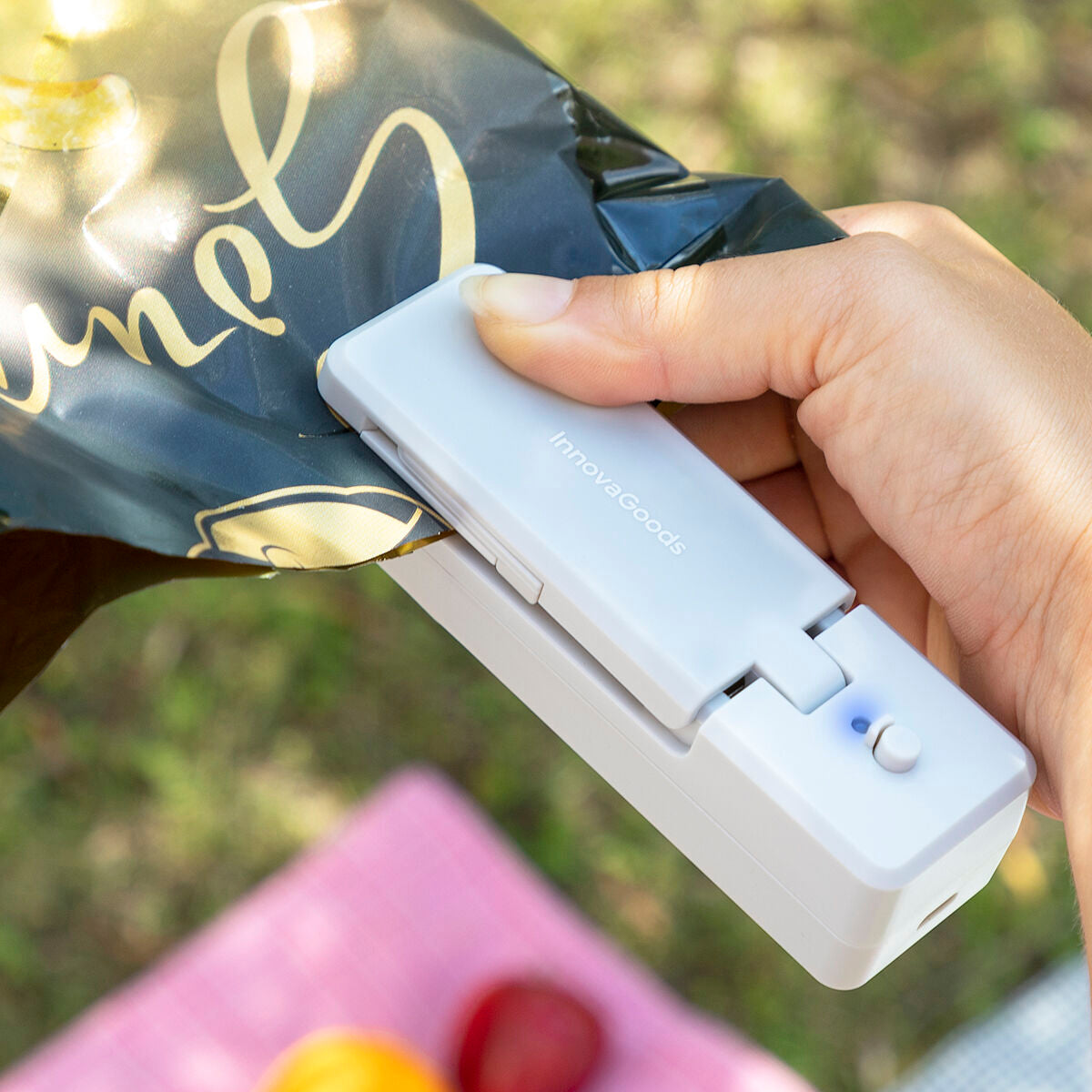 Hand verschließt mit dem grauen InnovaGoods Rebasyl den Rand eines dunklen Kunststoff-Snackbeutels