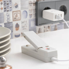 Grauer InnovaGoods Rebasyl mit geöffnetem Oberteil beim Laden über USB-Kabel an einer separaten Stromquelle