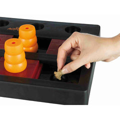 Hand legt einen Snack in eine Vertiefung des Chess-Spielbretts neben orangefarbenen Kegeln