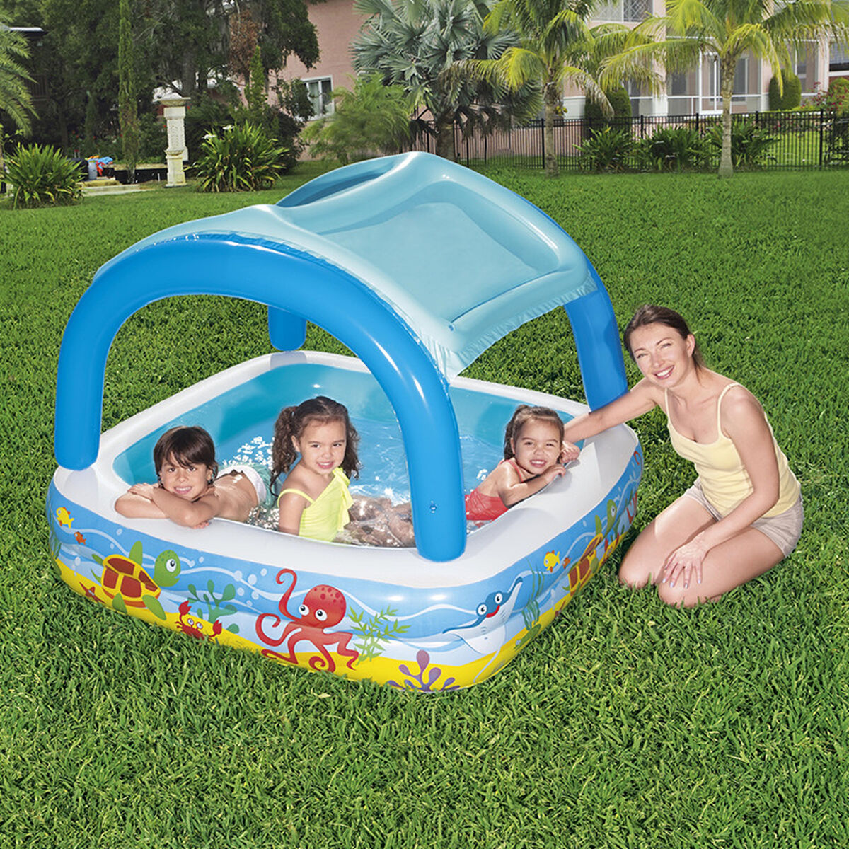 Kinder spielen im Bestway Beach Buddy Planschbecken mit Dach auf dem Rasen neben einer erwachsenen Aufsichtsperson