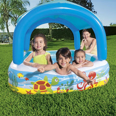 Vorderansicht des Bestway Beach Buddy Planschbeckens mit Meeresmotiven, Kindern und einer erwachsenen Aufsichtsperson im Garten