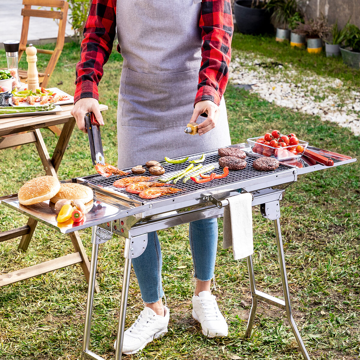 ExelQ-Edelstahlgrill mit Grillgut und ausgeklappten seitlichen Ablagen im Garten