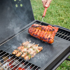 Schwarze Grillmatten auf einem geöffneten Grill mit Gemüse und Bratgut