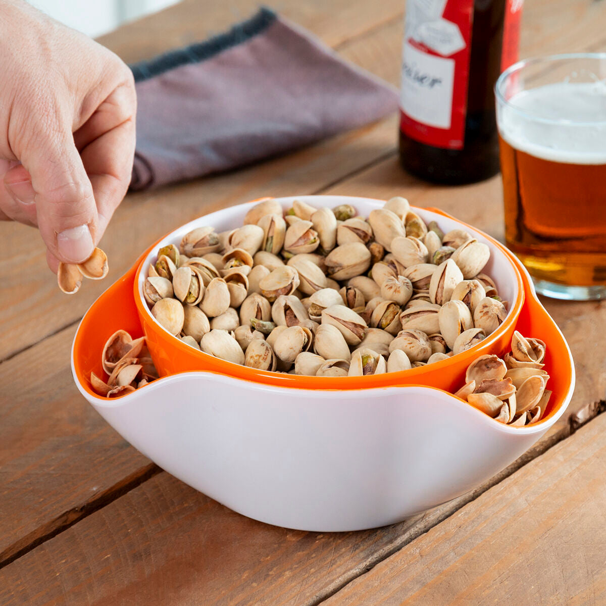 Gestapelte InnovaGoods Snackschalen mit Pistazien und einer zugreifenden Hand