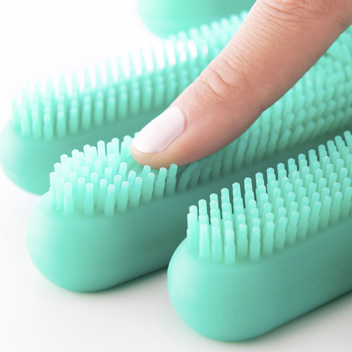 Ein Finger drückt auf die weichen Borsten eines grünen Silikonhandschuhs