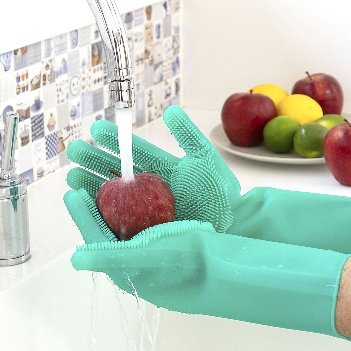Grüne Silikonhandschuhe halten einen Apfel unter fließendem Wasser