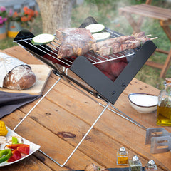 Foldecue-Mini-Grill mit Fleisch und Gemüse auf einer Außenfläche