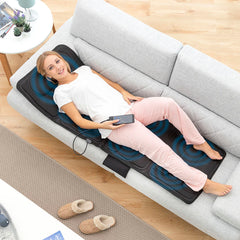 Person liegt auf der vollständig ausgebreiteten Vhemat-Massagematte auf einem Sofa
